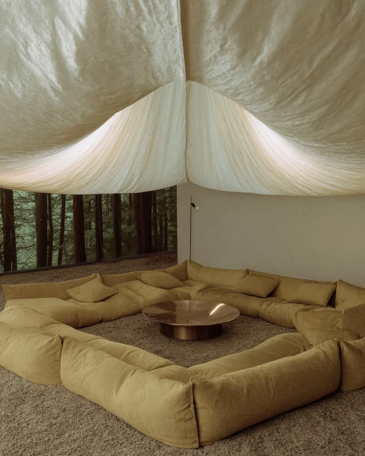 Relaxation lounge with low sand-coloured banquettes under a fabric ceiling