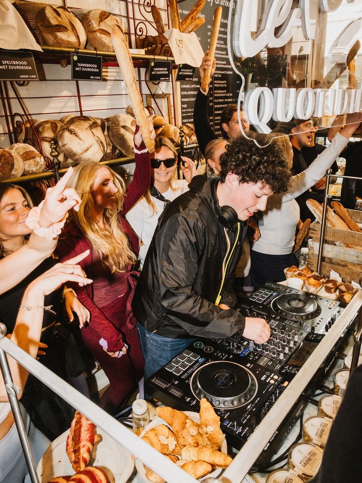 DJ qui mixe derrière le comptoir d'une boulangerie, entouré de pains et de croissants