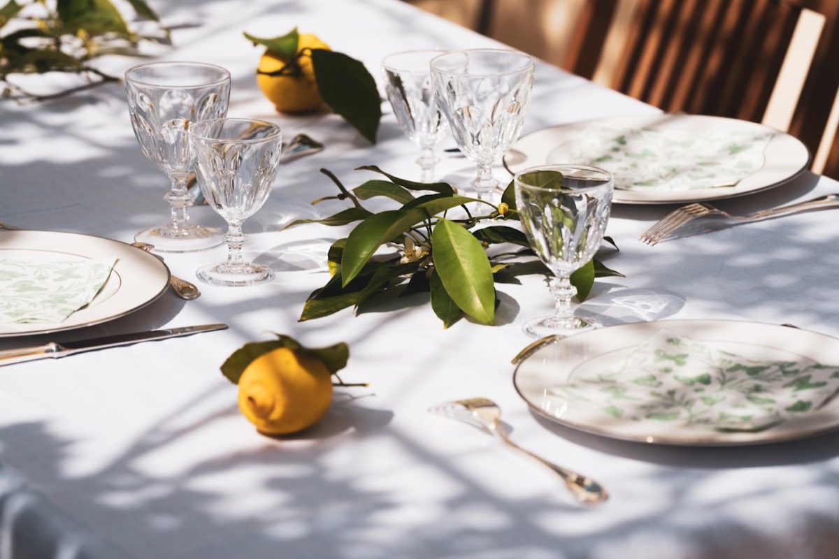 Table dressée en extérieur avec verres en cristal, feuillage et fruits locaux, événement écoresponsable